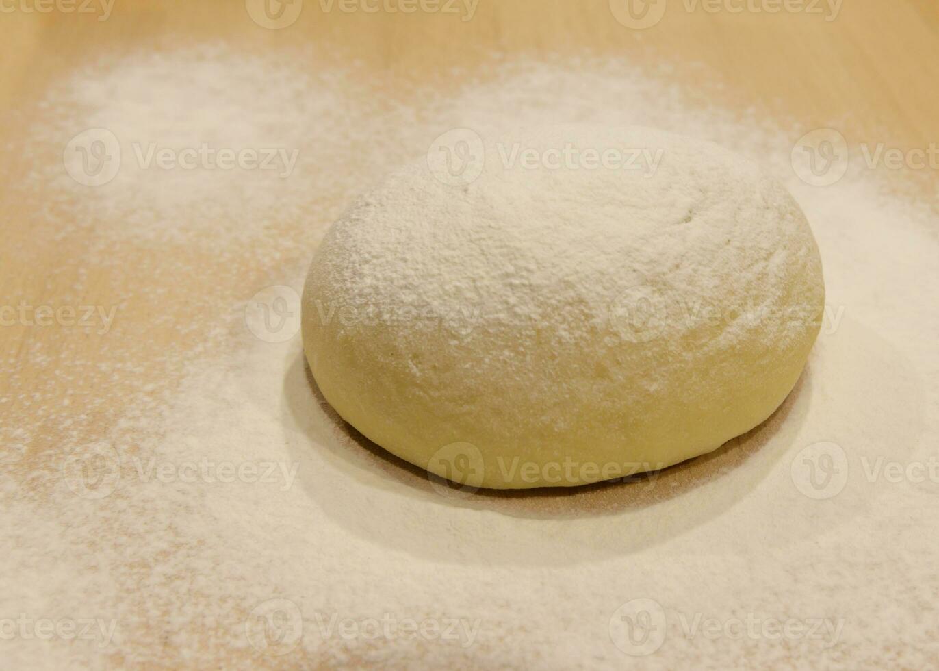 rounded piece of yeast dough sprinkled with flour is on the table. selective focus. High quality photo