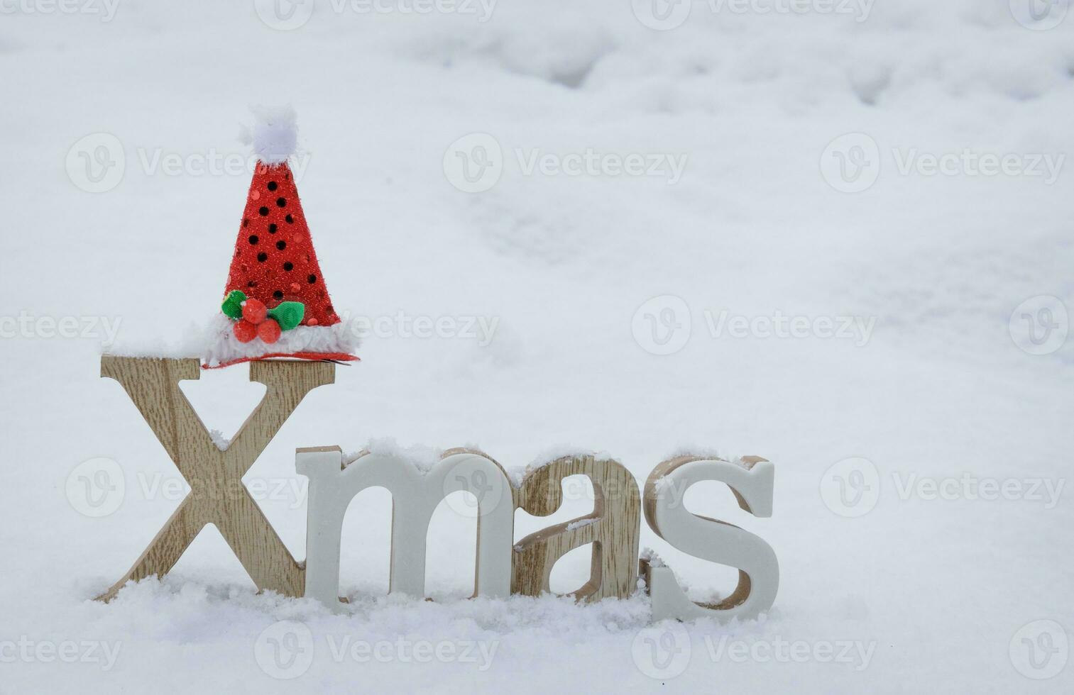 wooden Christmas decoration stands on white snow and Santa red hat on it. selective focus .High quality photo