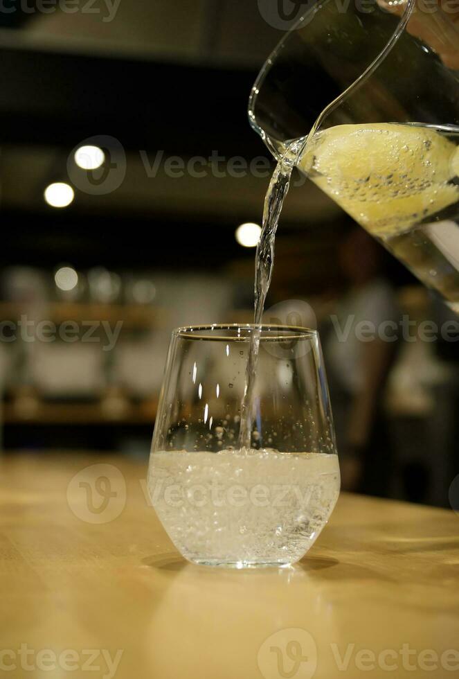 glass jug from which citrus lemonade is poured into a glass. selective focus.High quality photo