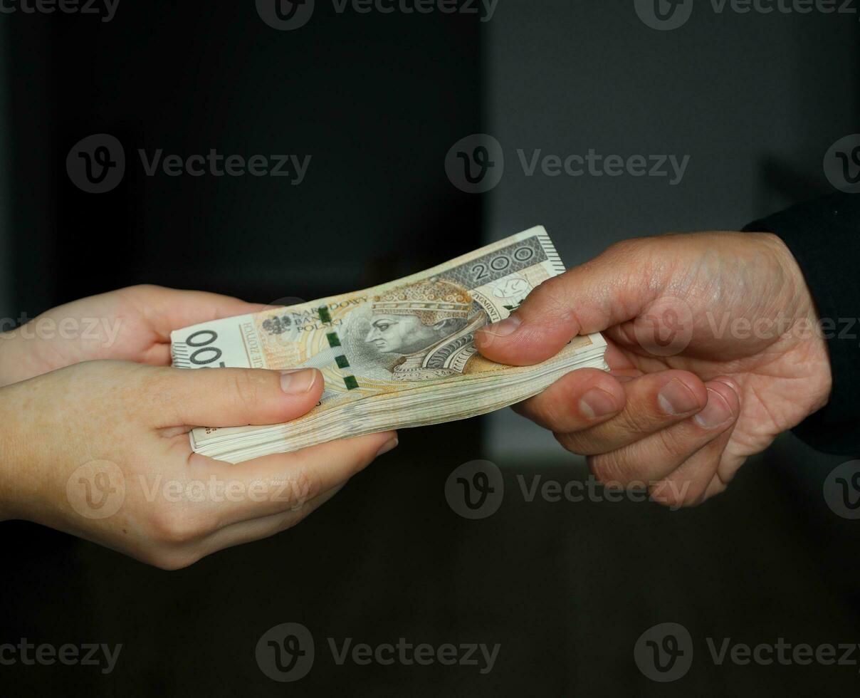 male hand giving a bundle of large banknotes to female hands. selective focus photo