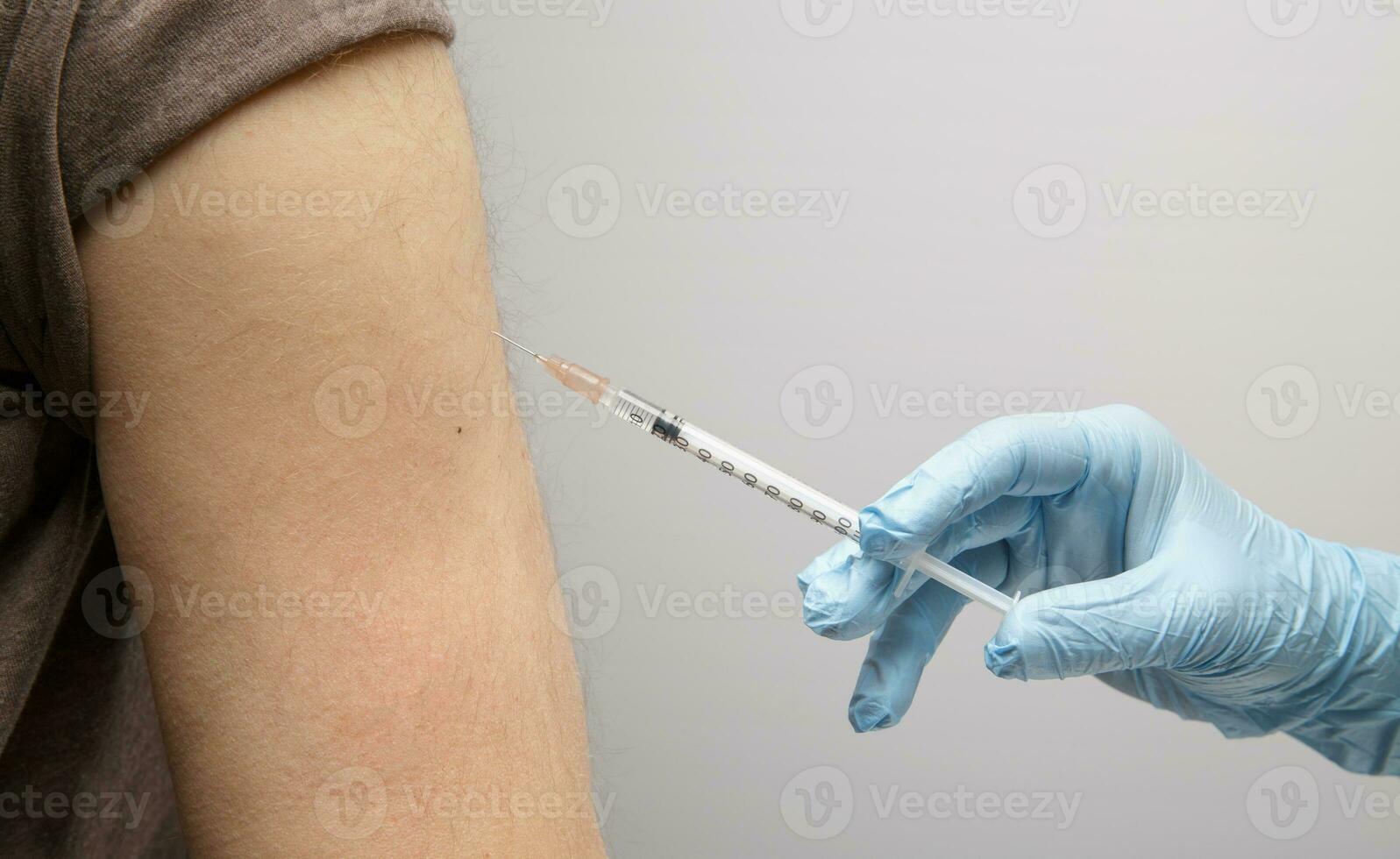 the hand of a paramedic makes an injection of a vaccine to an invisible person. health concept. protection against coronavirus photo