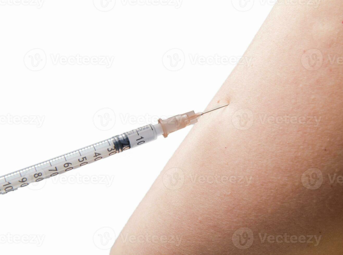 close up of vaccination with syringe in upper arm . High quality photo . focus on the needle white background