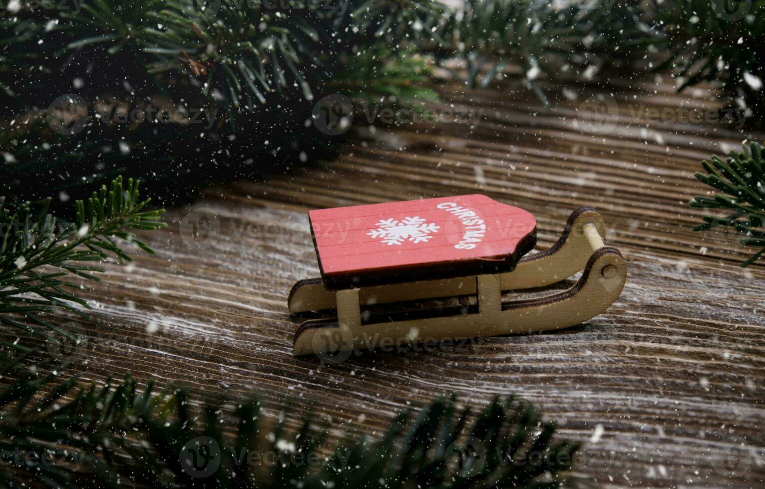 red wooden sled stand between fir branches. Christmas tree toys. concept for Christmas and new year holidays. snow falls.selective focus.High quality photo