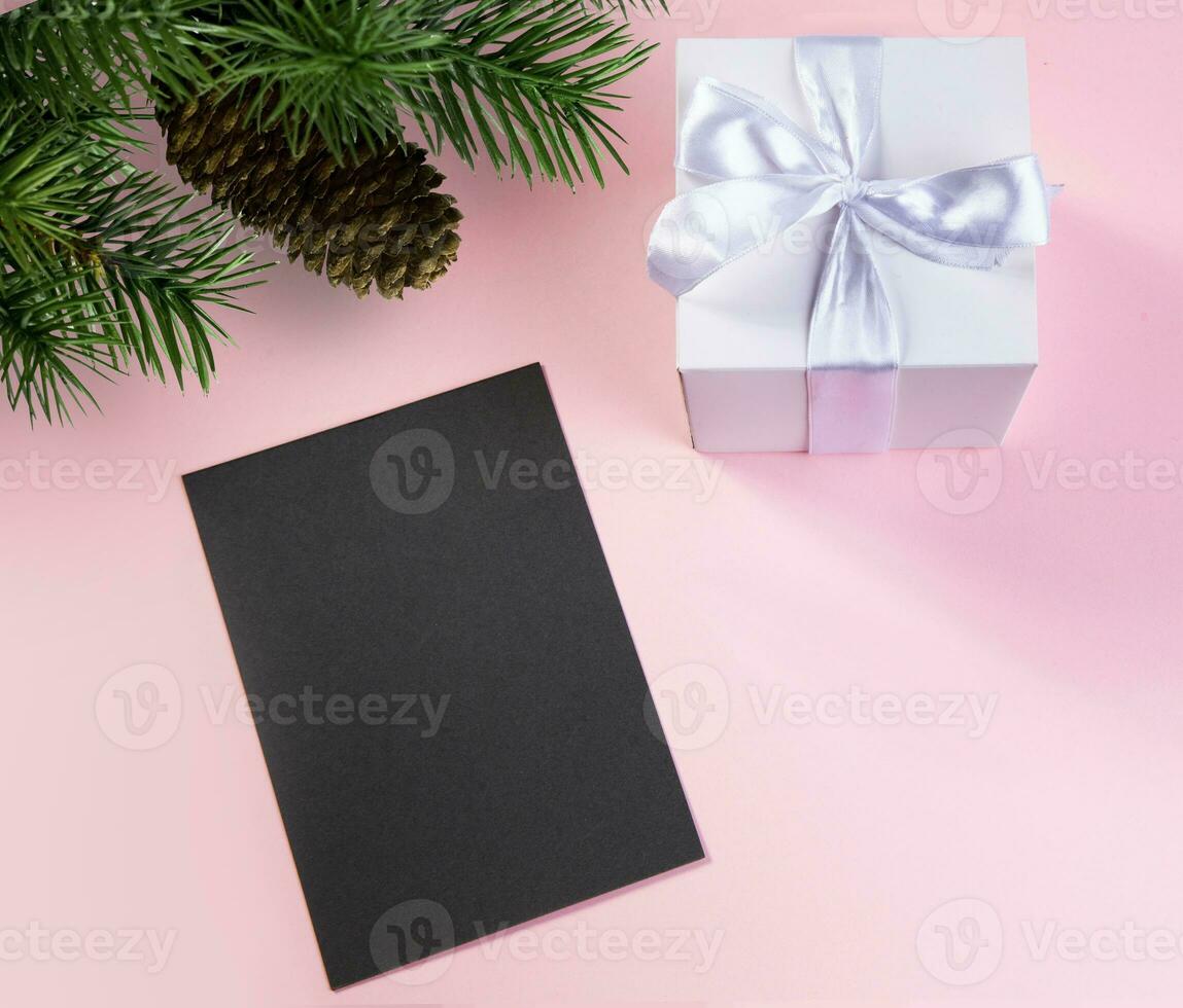 gift box with white silk ribbon fir branch with pine cone and dark card for text .concept holiday.selective focus. photo