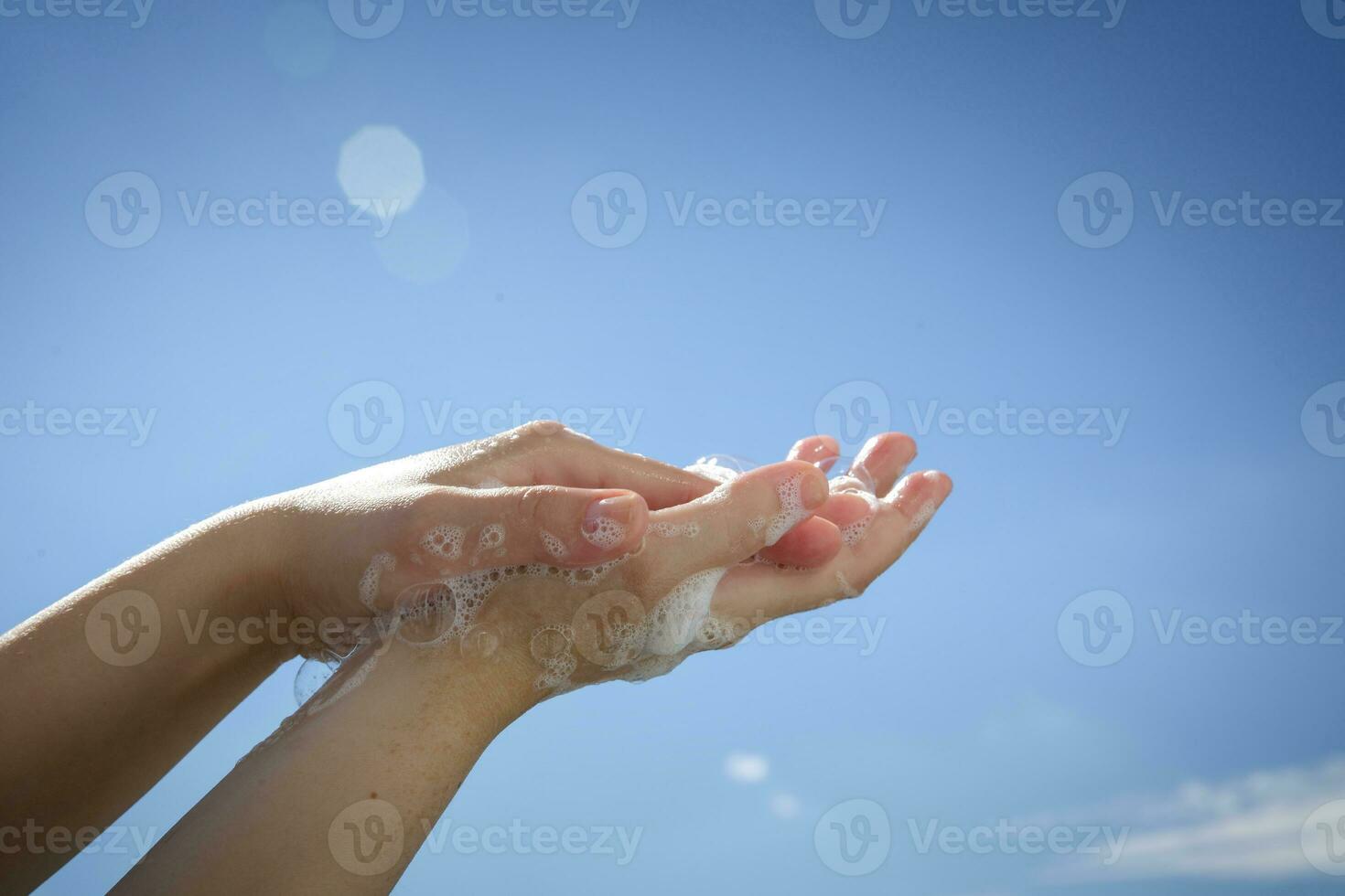 Closeup of Caucasian woman hands while washing hands with soap on blue sky background . Top view . Hygiene .Cleaning hands . Hygiene concept hand detail coronavirus protective measure photo