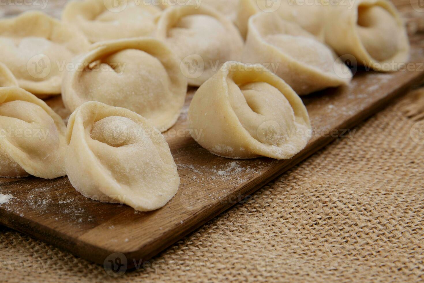 wooden food board with dumplings stands on burlap on the table. selective focus photo