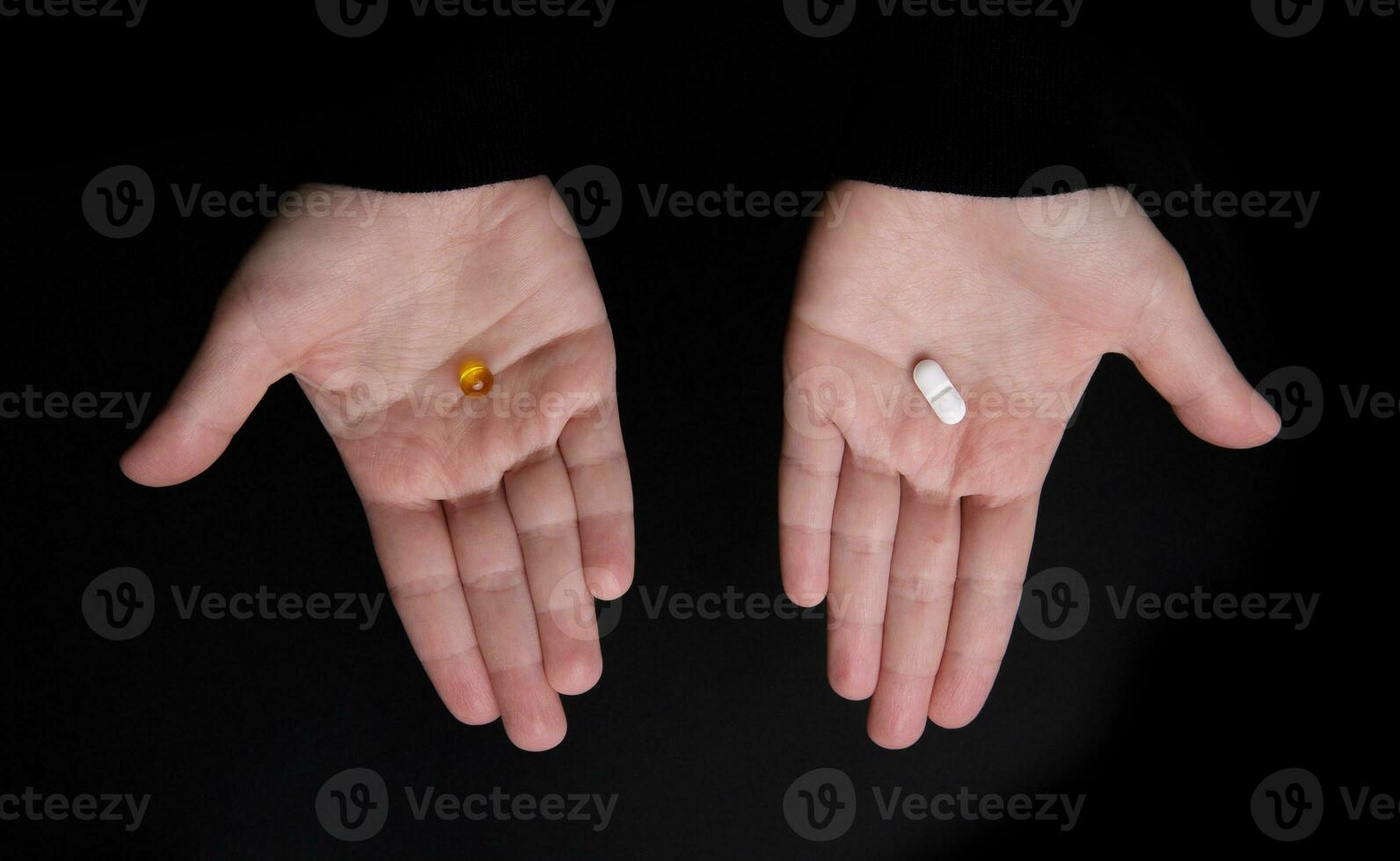 cápsula con omega 3 y un píldora en dos palmas en un negro antecedentes. selectivo atención foto