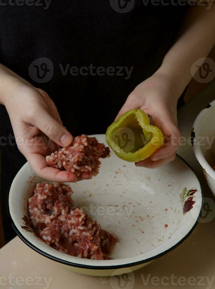 mujer manos llena el campana pimientos con picado carne. paso por paso preparación . cena . selectivo suave atención . proceso Cocinando . foto