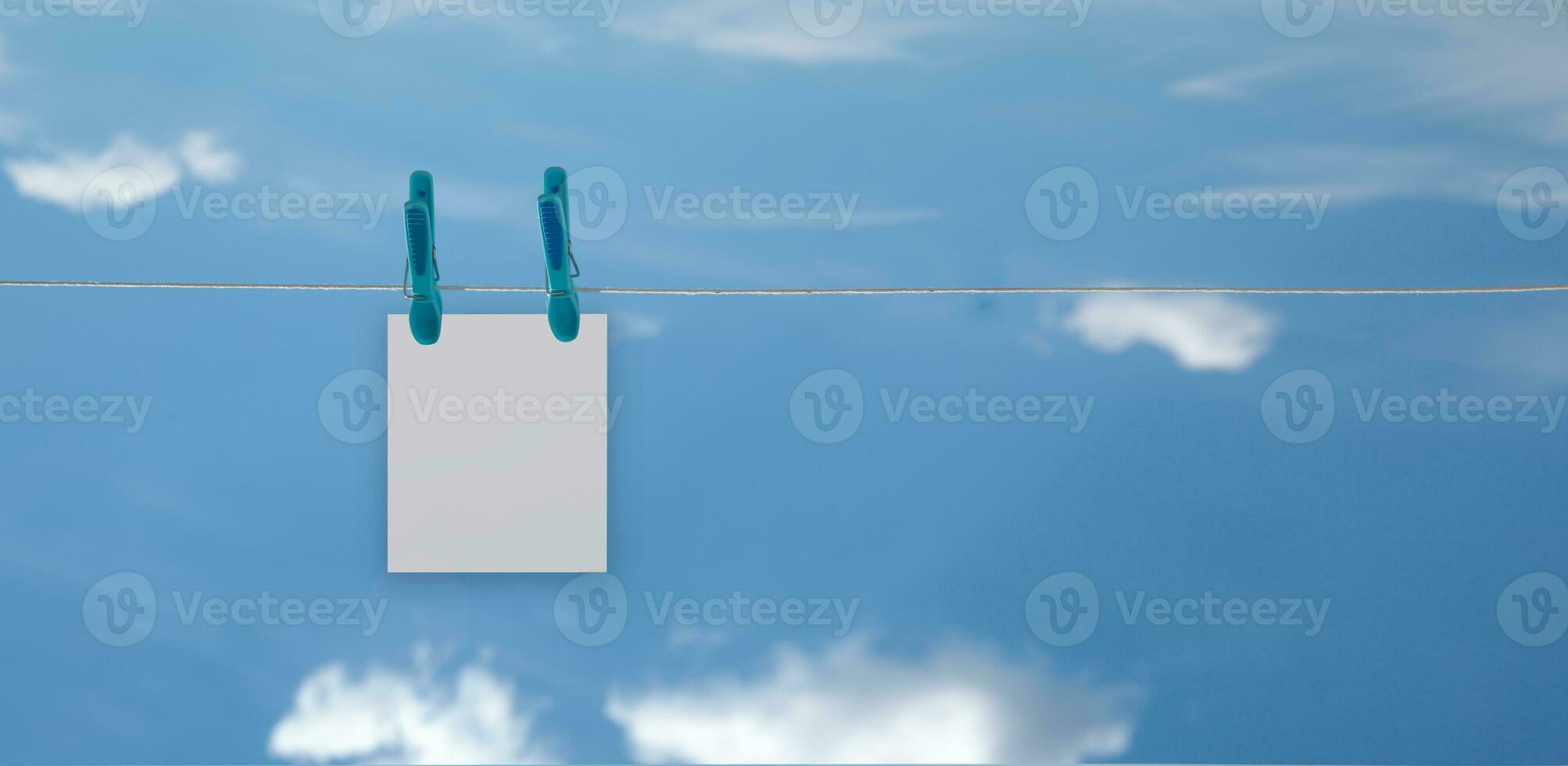 blank notes hanging on a rope with a clothespin with a bright sky background with clouds. High quality photo