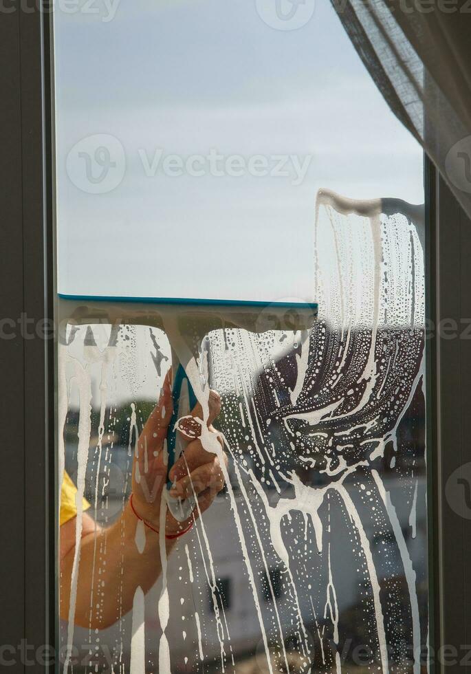 a man washes a window on a balcony on a sunny day. photo