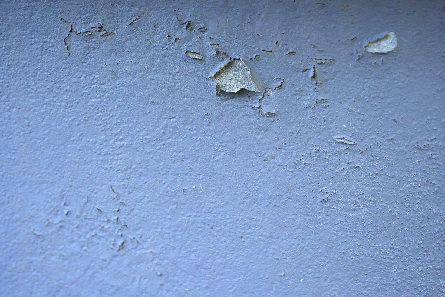 White peeling paint wall surface with moldy.Weathered concrete pattern wall.Old white color painted peeling off moment to do can see raw concrete texture wall.Swelling concrete wall texture. photo