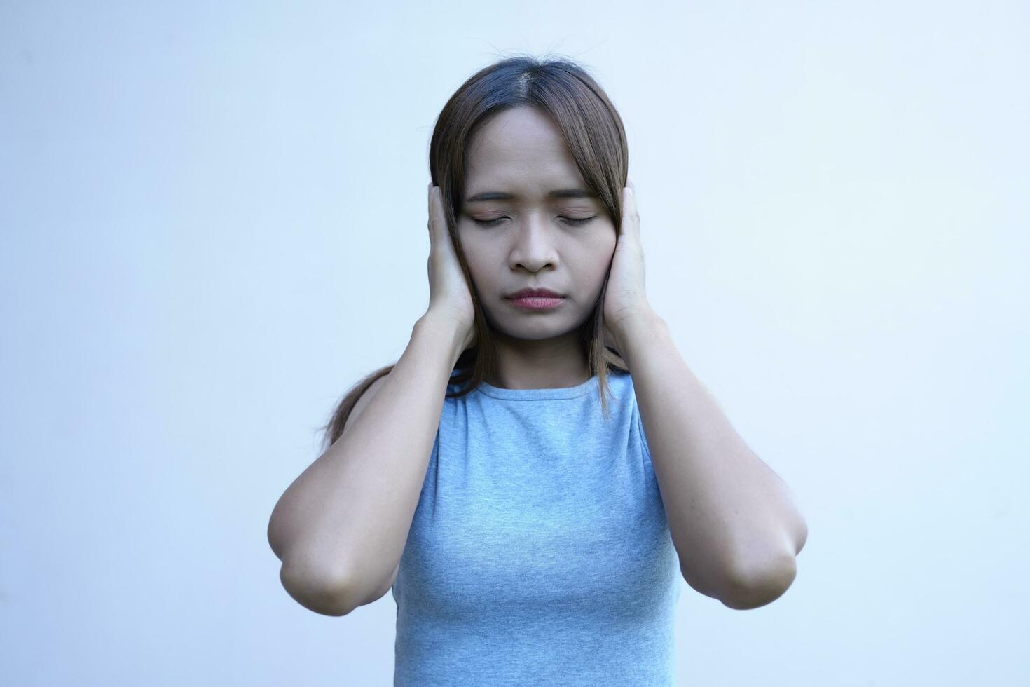 Asian woman covers her ears with her hands to prevent hearing photo