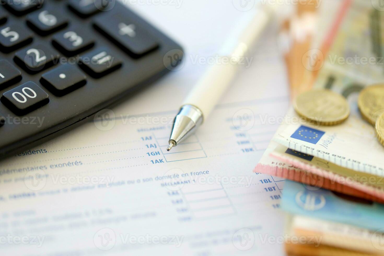 Filling french tax form process with calculator, pen and euro money bills close up. Tax paying period photo