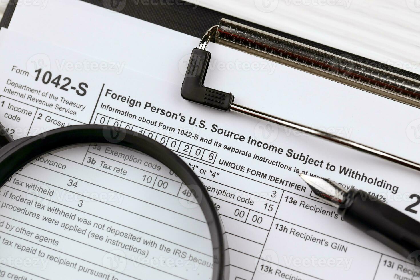 IRS Form 1042-S Foreign persons US source income subject of withholding blank on A4 tablet lies on office table with pen and magnifying glass photo