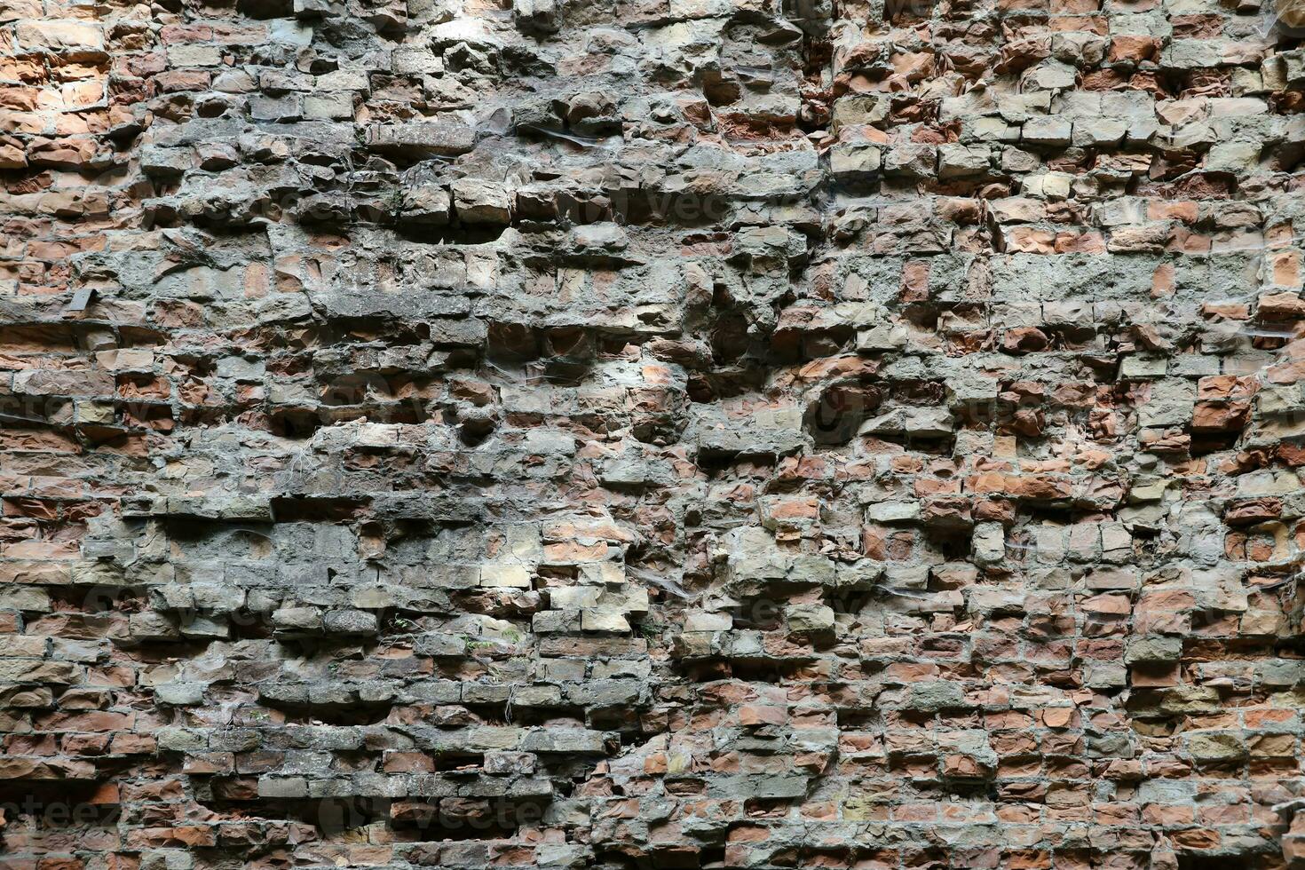 Very old brick stone wall of castle or fortress of 18th century. Full frame wall with obsolete dirty and cracked bricks photo