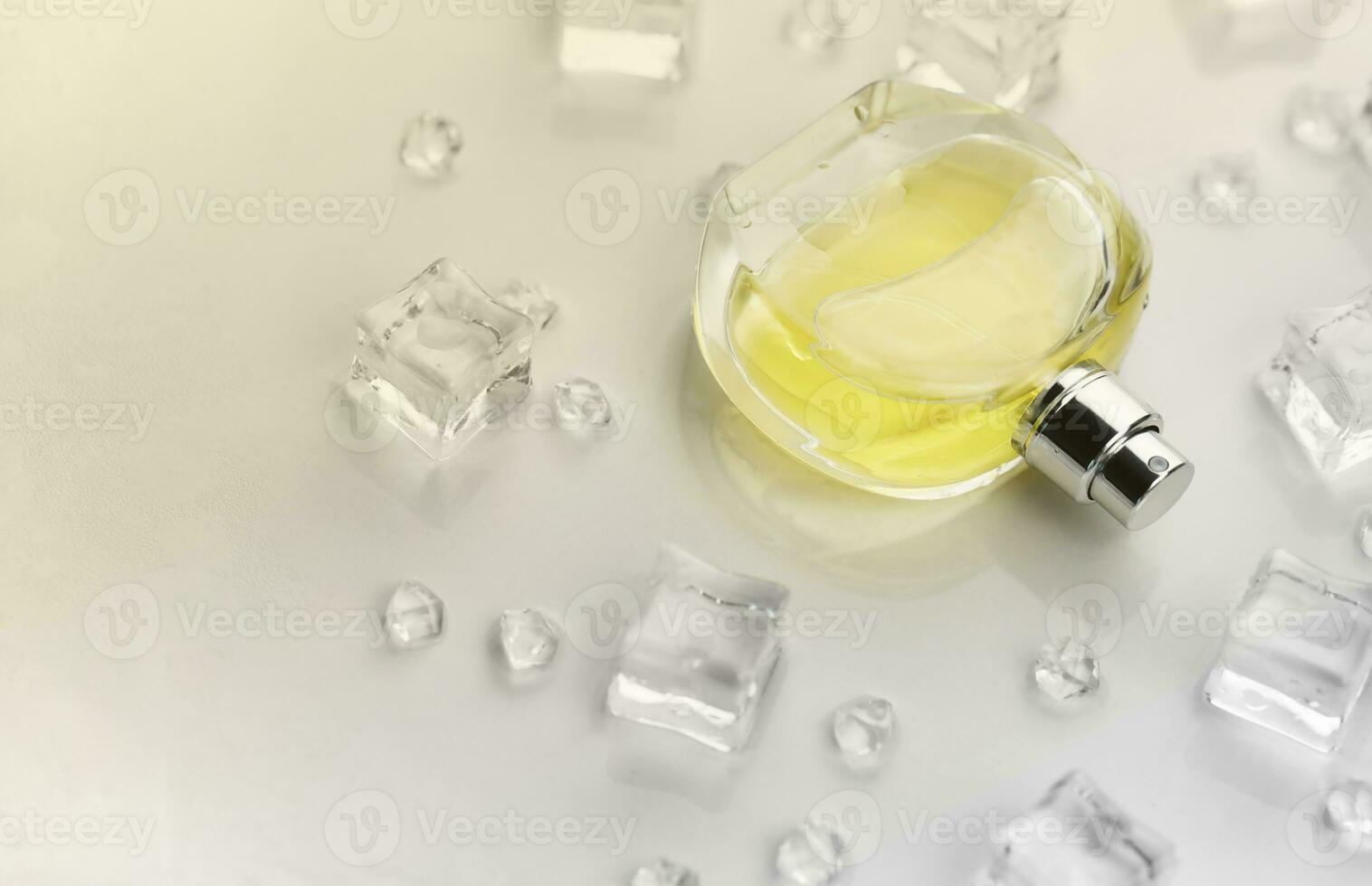 Female perfume yellow bottle, Objective photograph of perfume bottle in ice cubes and water on white table. View from above. Mockup product photo, concept of freshness photo