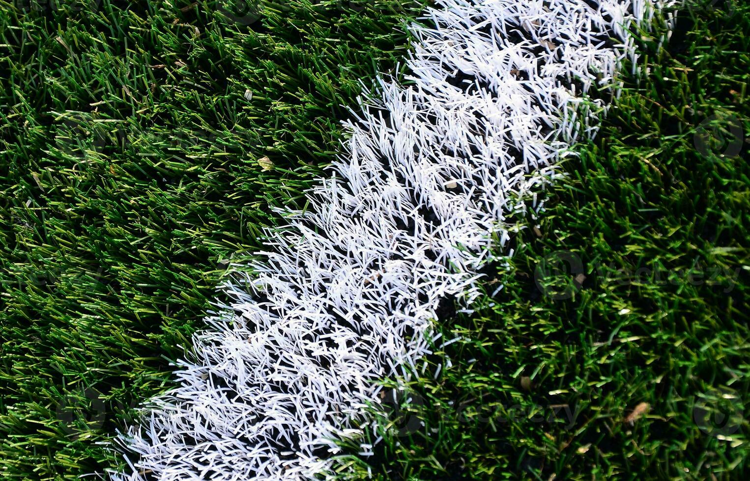 White stripe on a bright green artificial grass soccer field photo
