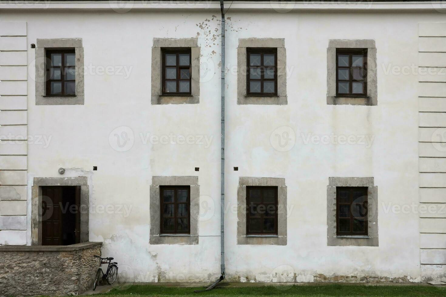 Glass windows on white antique wall of old medieval castle in european suburb photo