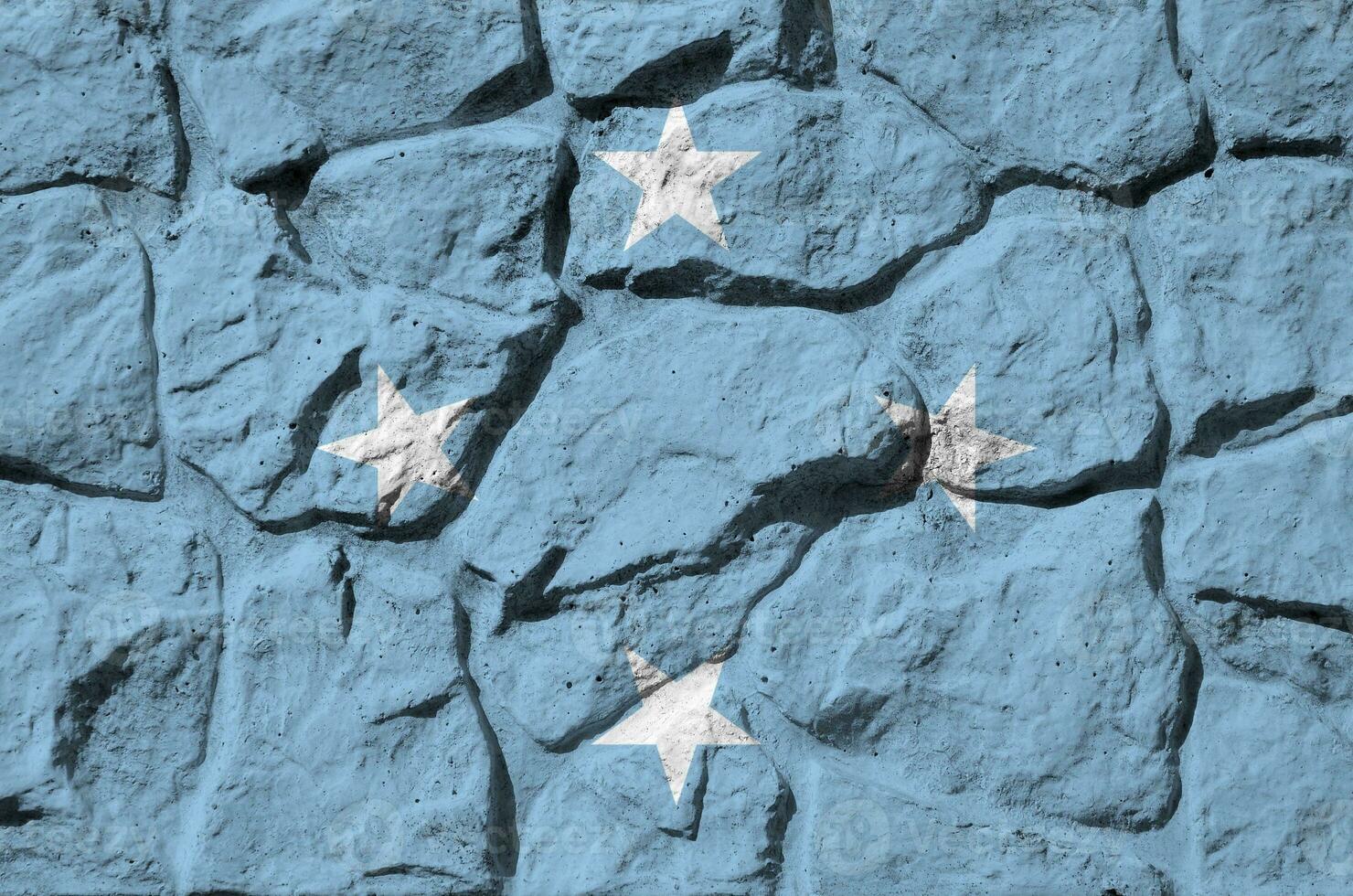 Micronesia flag depicted in paint colors on old stone wall closeup. Textured banner on rock wall background photo