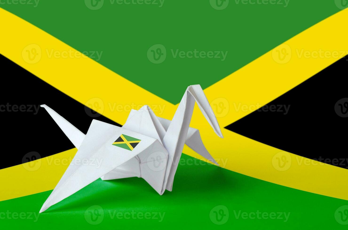 Jamaica flag depicted on paper origami crane wing. Handmade arts concept photo