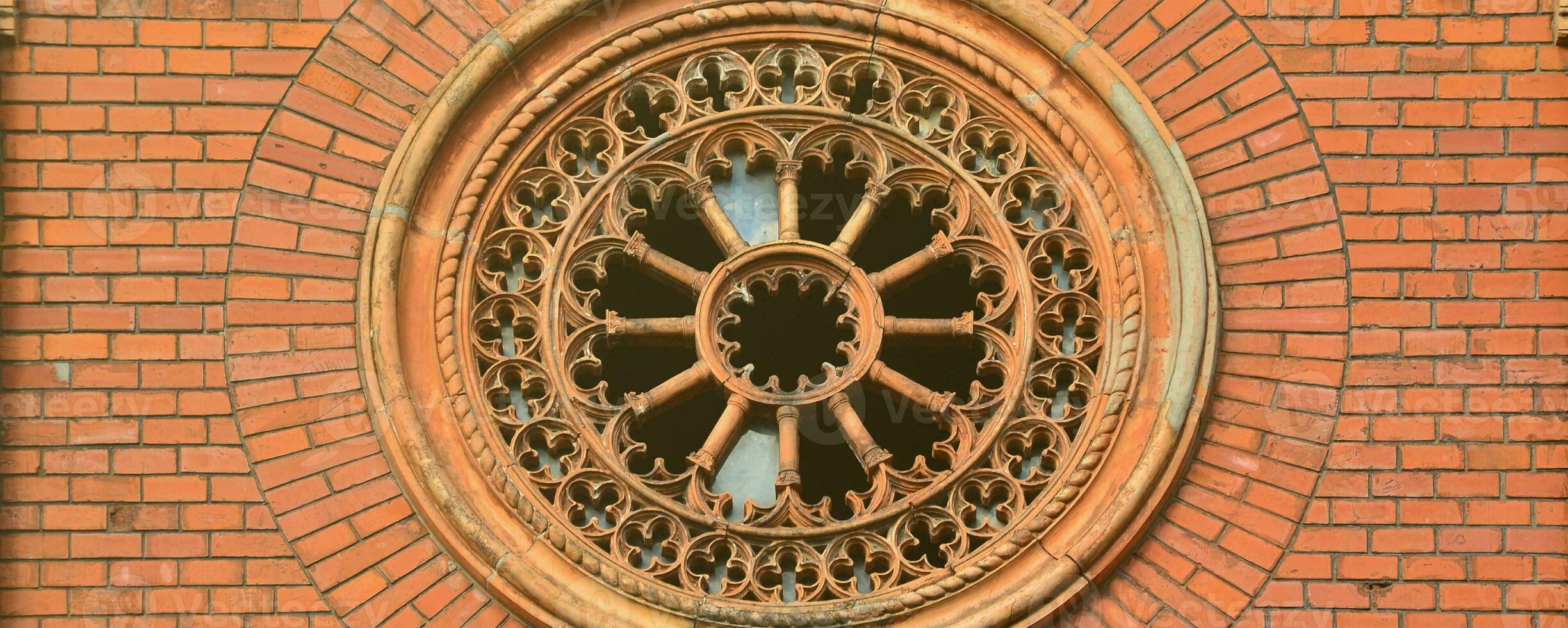 Texture front part of an ancient brick crypt with a round patterned carved window in the cemetery photo