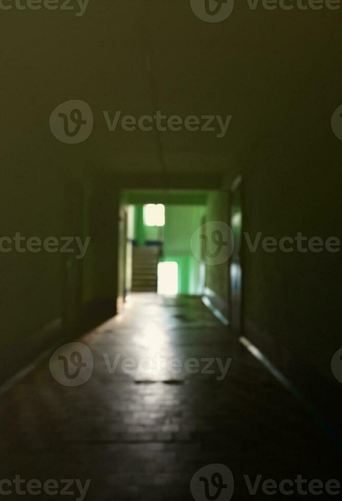 The blurred image of gloomy corridor of a neglected public building. Defocused picture of a public space in a poor residential high-rise building photo