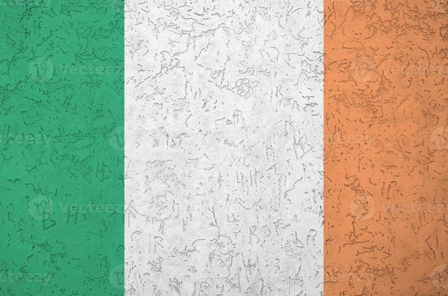 Ireland flag depicted in bright paint colors on old relief plastering wall. Textured banner on rough background photo