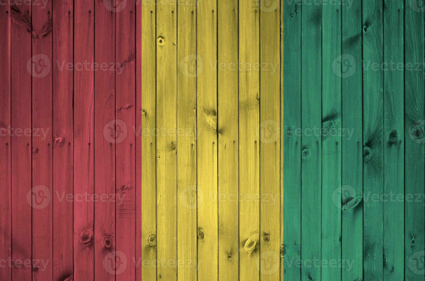 Guinea flag depicted in bright paint colors on old wooden wall. Textured banner on rough background photo