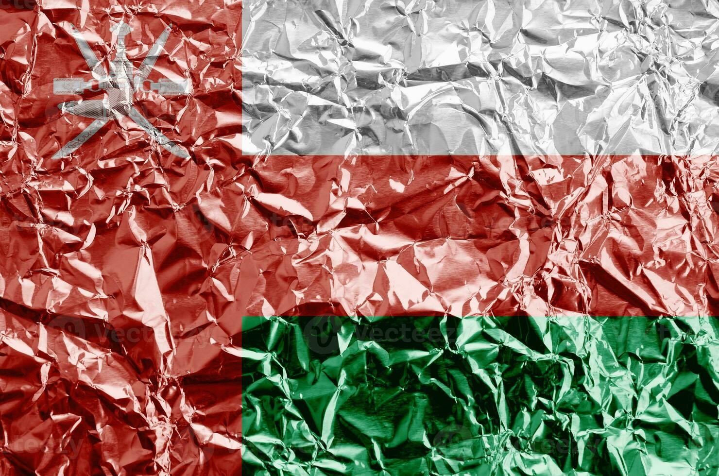 Oman flag depicted in paint colors on shiny crumpled aluminium foil closeup. Textured banner on rough background photo