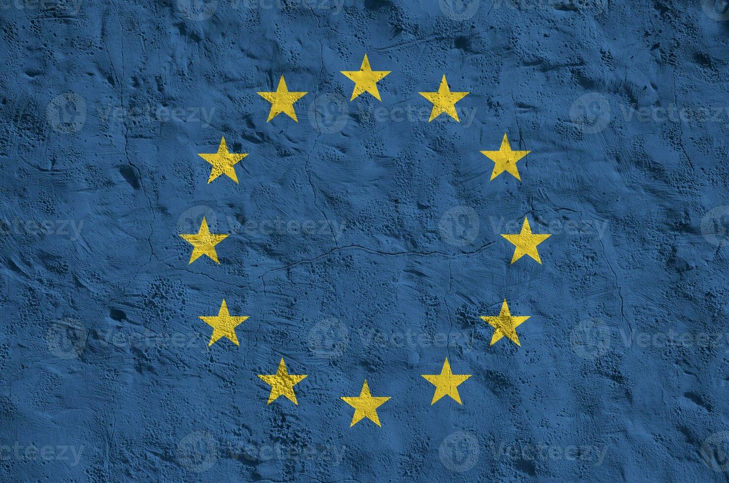 European union flag depicted in bright paint colors on old relief plastering wall. Textured banner on rough background photo