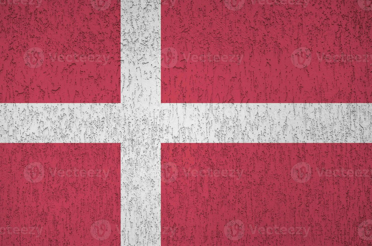 Denmark flag depicted in bright paint colors on old relief plastering wall. Textured banner on rough background photo