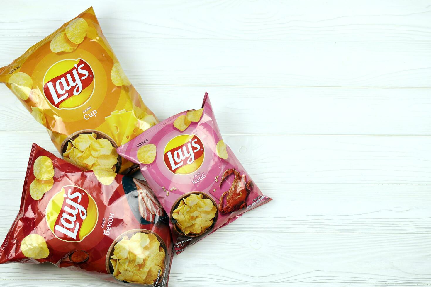 KHARKOV, UKRAINE - JANUARY 3, 2021 Various flavoured of lay's potato chips on wooden background. Lay's has been owned by PepsiCo through Frito-Lay in 1965 photo