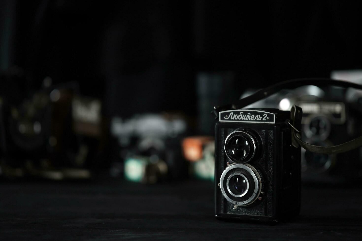 KHARKOV, UKRAINE - APRIL 27, 2021 Lubitel 166b and 2 Film photo camera and another old retro photo equipment on black wooden table in photographer darkroom. Photographic gear from soviet union