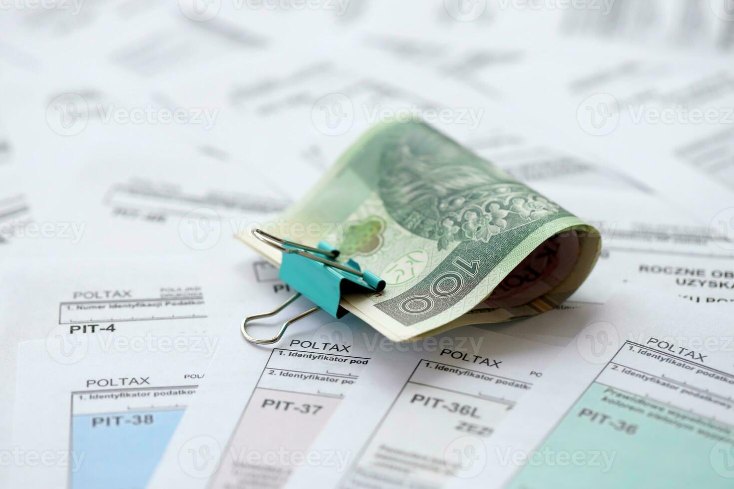 Polish zloty money PLN on big amount of polish PIT, CIT and VAT tax forms close up. Accounting, bureaucracy and taxpayers routine photo