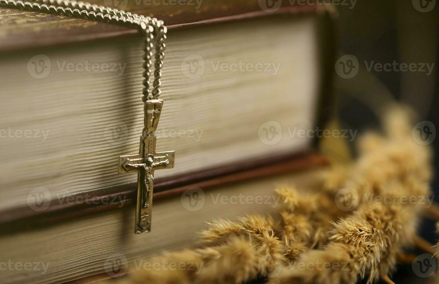 Silver necklace with crucifix cross on christian holy bible book on black wooden table. Asking blessings from God with the power of holiness photo