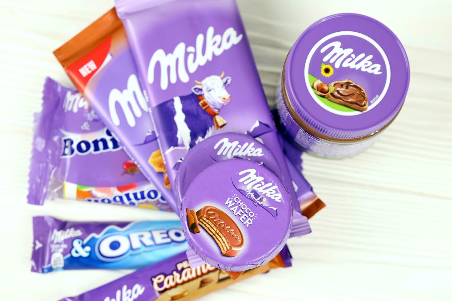 kharkov, ucrania - 2 de julio de 2021 productos de chocolate milka con diseño de envoltura de color lila clásico en mesa blanca foto