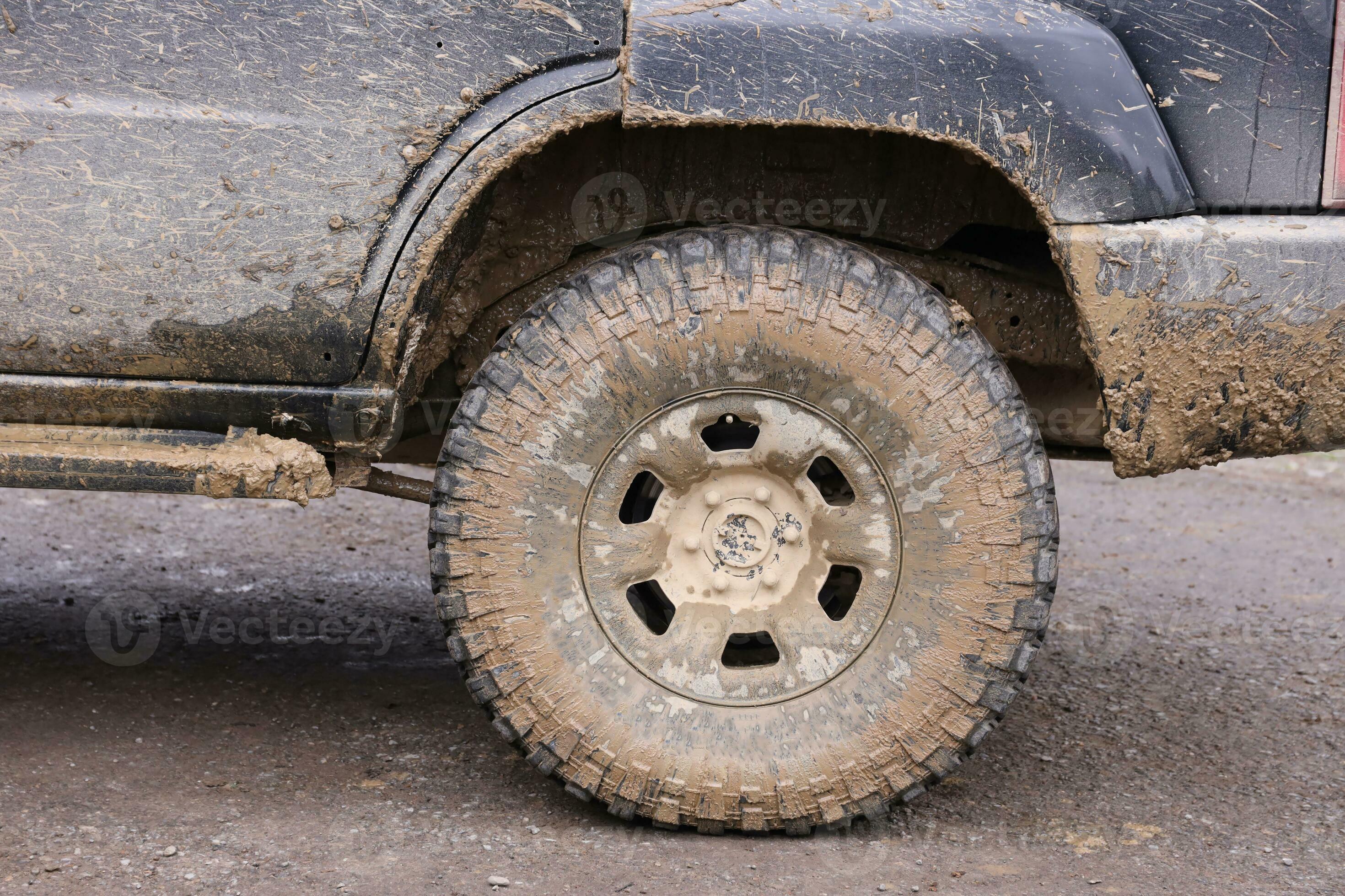 Wheel closeup in a countryside landscape with a mud road. Offroad 4x4