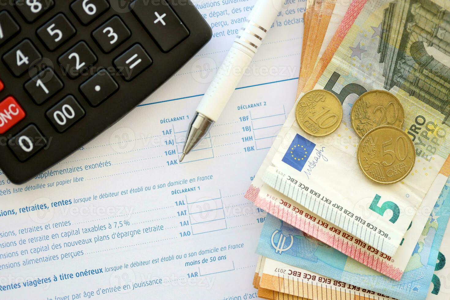 Filling french tax form process with calculator, pen and euro money bills close up. Tax paying period photo