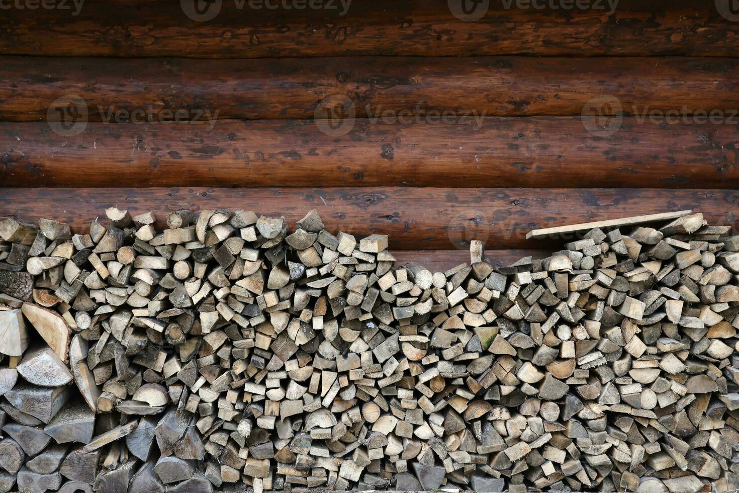 Firewood stacked near the wooden wall of old hut. Many chopped logs of firewood photo