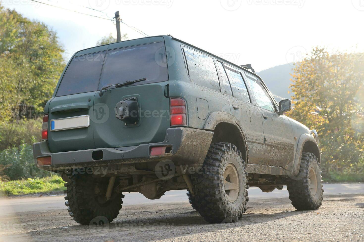 Automobile in a countryside landscape with a mud road. Off-road 4x4 suv automobile with ditry body after drive in muddy road photo
