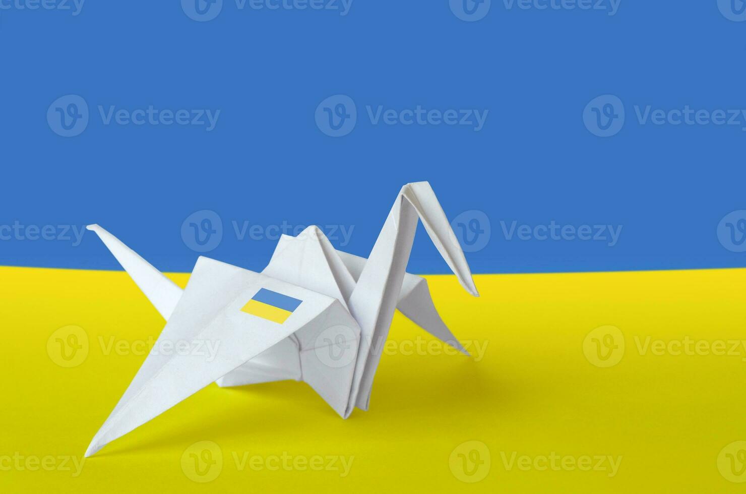 Ukraine flag depicted on paper origami crane wing. Handmade arts concept photo