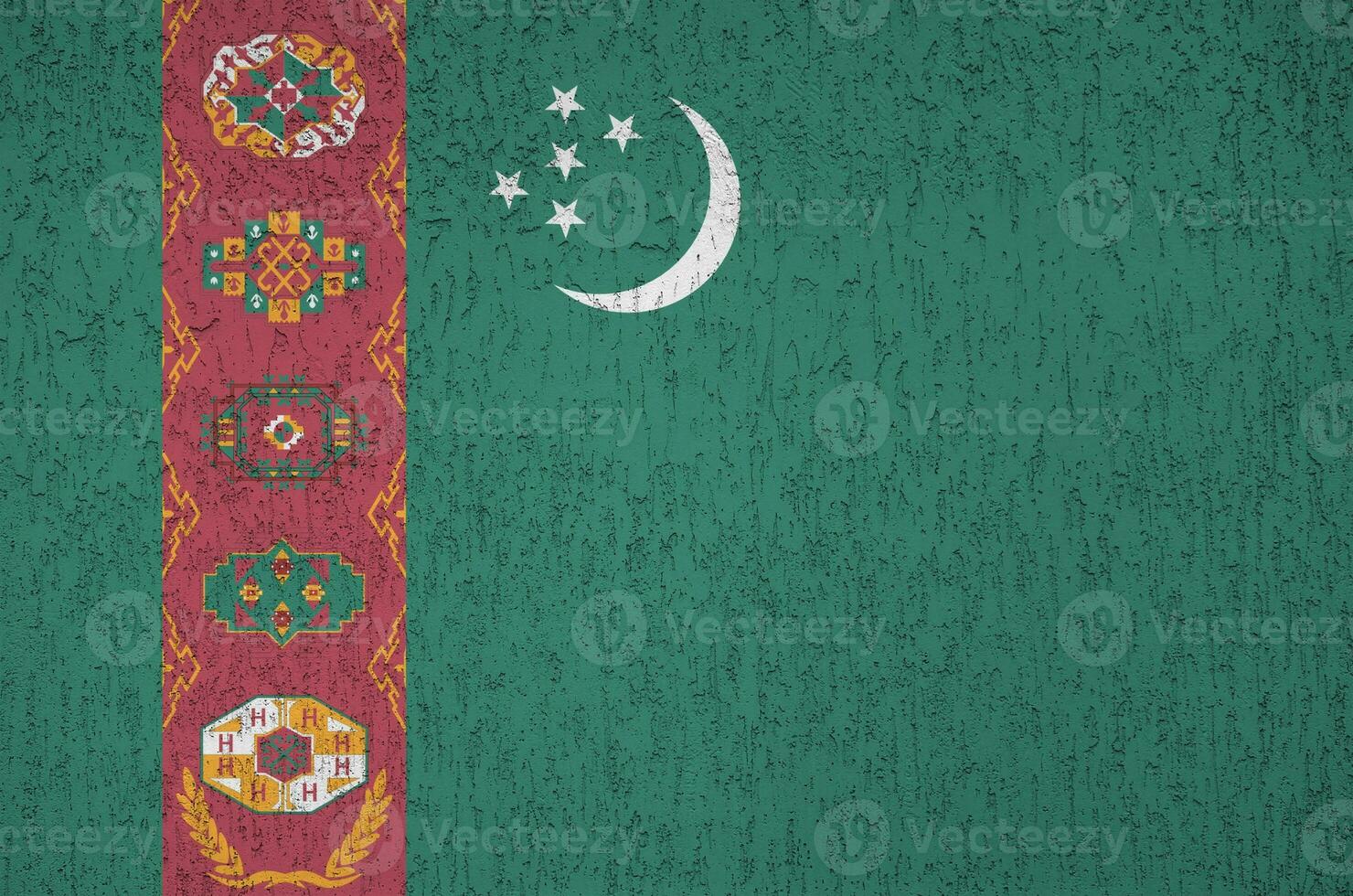 Turkmenistan flag depicted in bright paint colors on old relief plastering wall. Textured banner on rough background photo