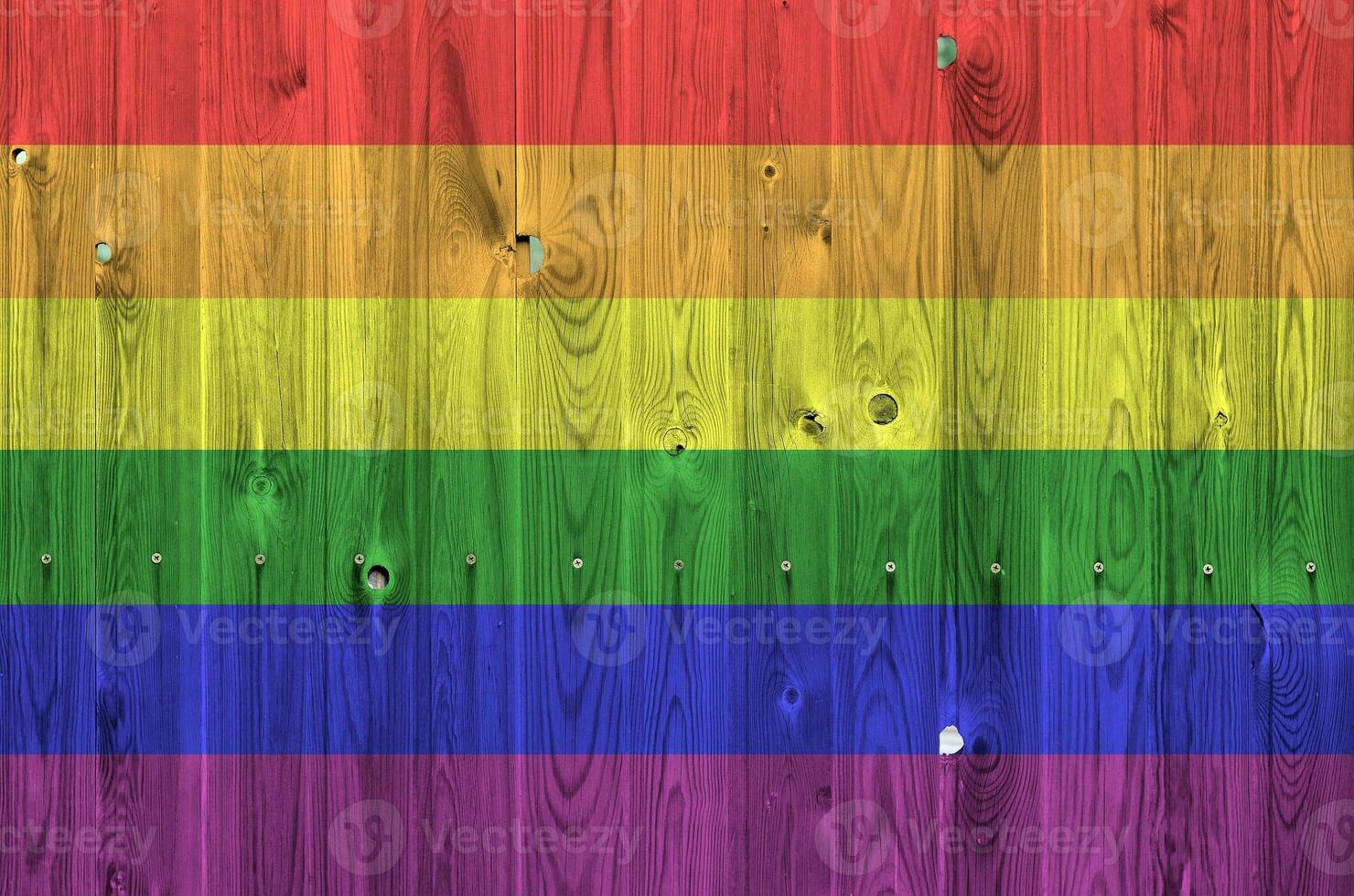 LGBT community flag depicted in bright paint colors on old wooden wall. Textured banner on rough background photo