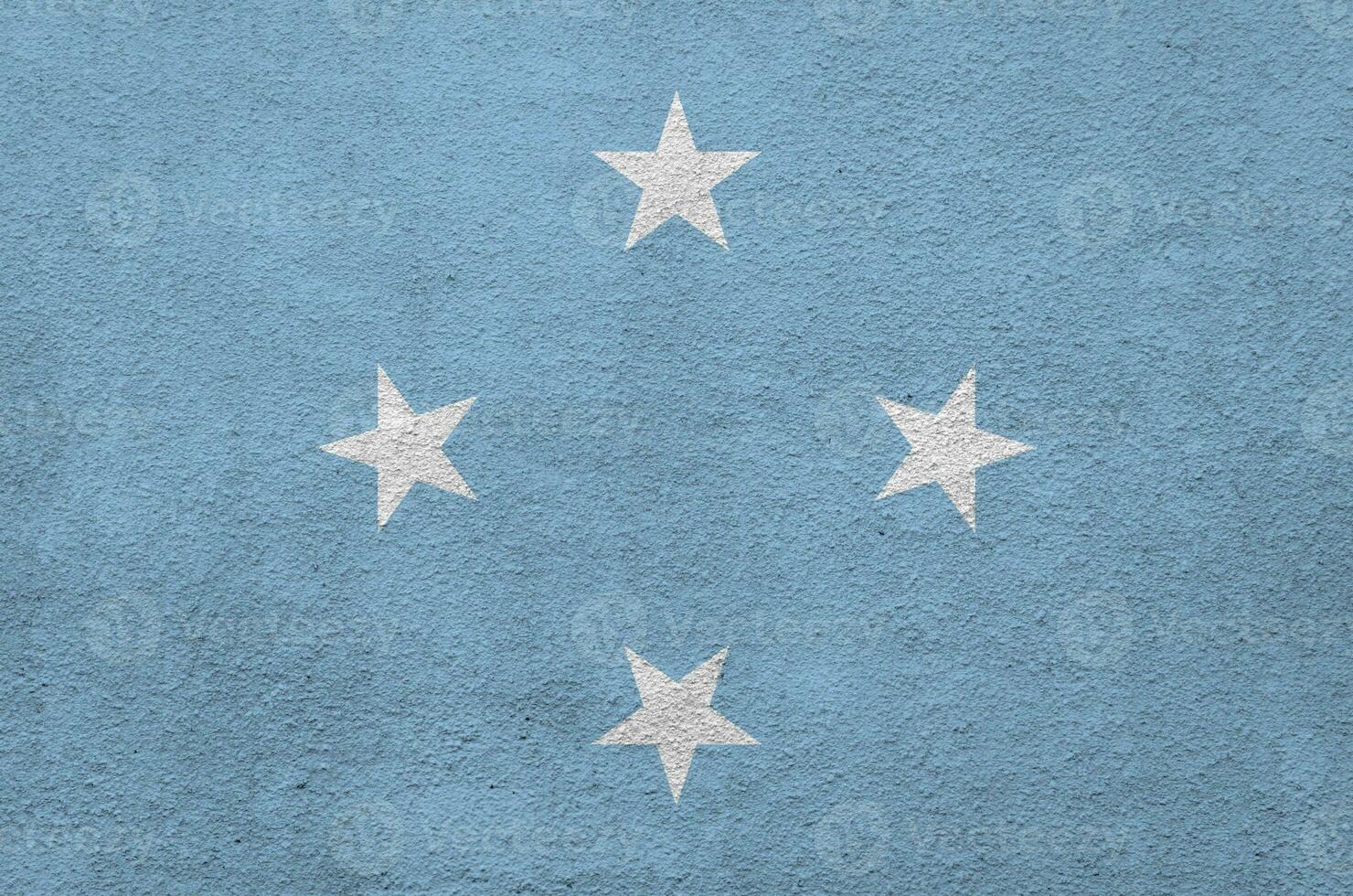 Micronesia flag depicted in bright paint colors on old relief plastering wall. Textured banner on rough background photo