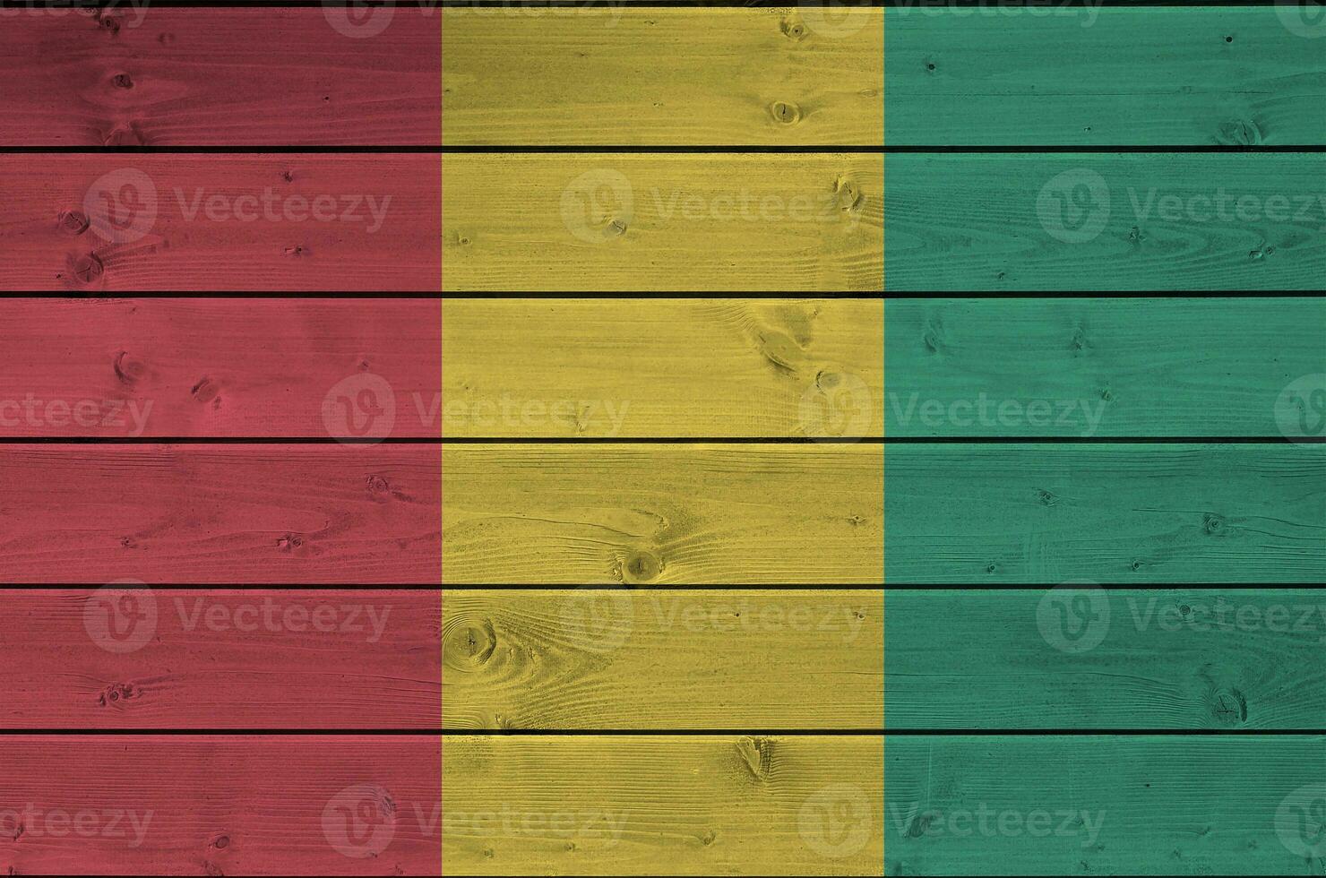 Guinea flag depicted in bright paint colors on old wooden wall. Textured banner on rough background photo