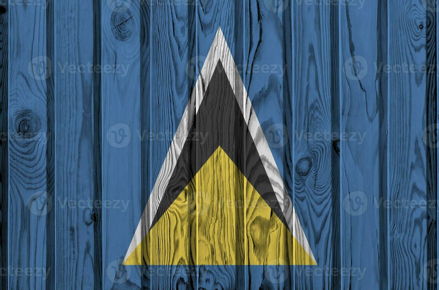 Saint Lucia flag depicted in bright paint colors on old wooden wall. Textured banner on rough background photo