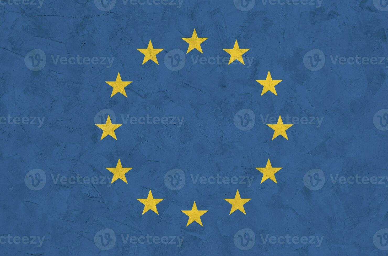 European union flag depicted in bright paint colors on old relief plastering wall. Textured banner on rough background photo