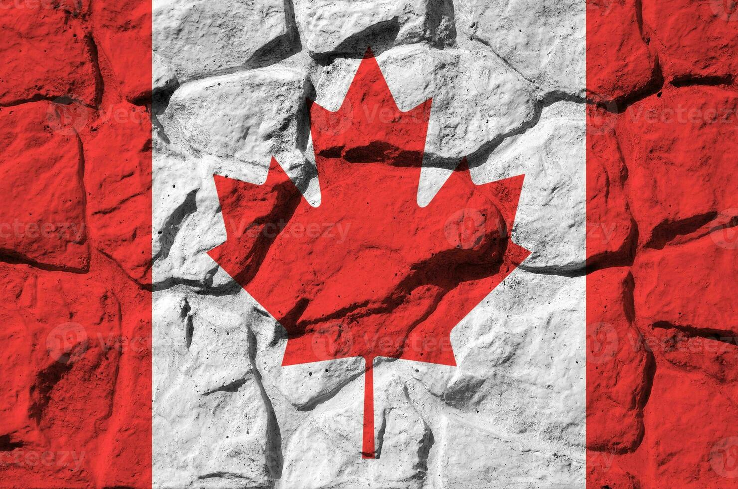 Canada flag depicted in paint colors on old stone wall closeup. Textured banner on rock wall background photo