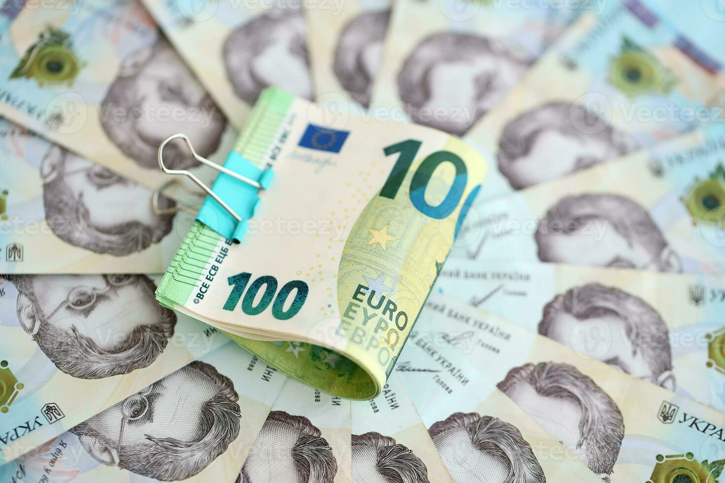 Bunch of hundred euro bills lies on many banknotes of ukrainian hryvnias. Economical default, crisis and devaluation of ukrainian national currency photo