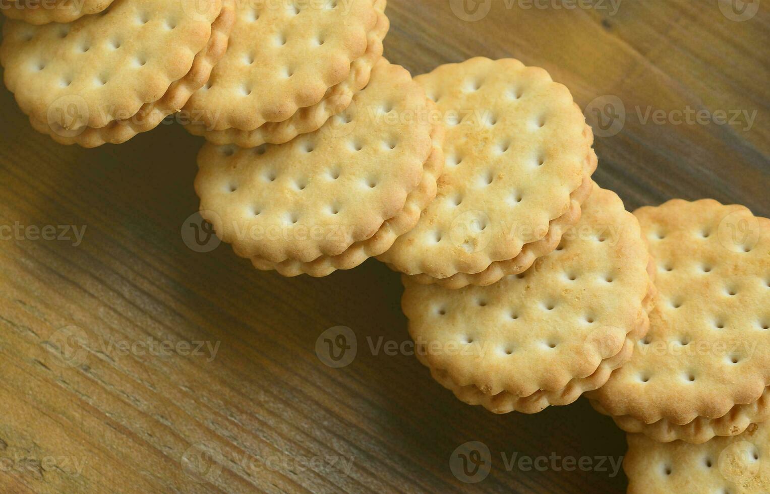 A round sandwich cookie with coconut filling lies in large quantities on a brown wooden surface. Photo of edible treats on a wooden background with copy space